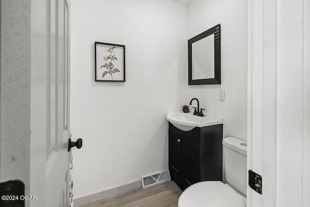 bathroom featuring toilet, vanity, and hardwood / wood-style flooring