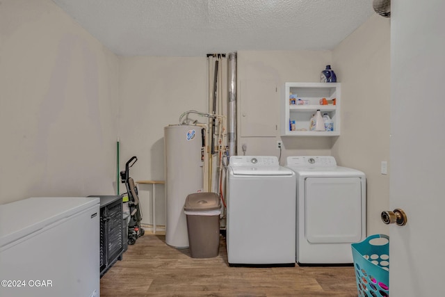 clothes washing area with a textured ceiling, washer and dryer, gas water heater, and light wood-type flooring