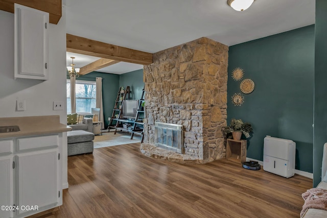 living room with beamed ceiling, a fireplace, and light hardwood / wood-style flooring