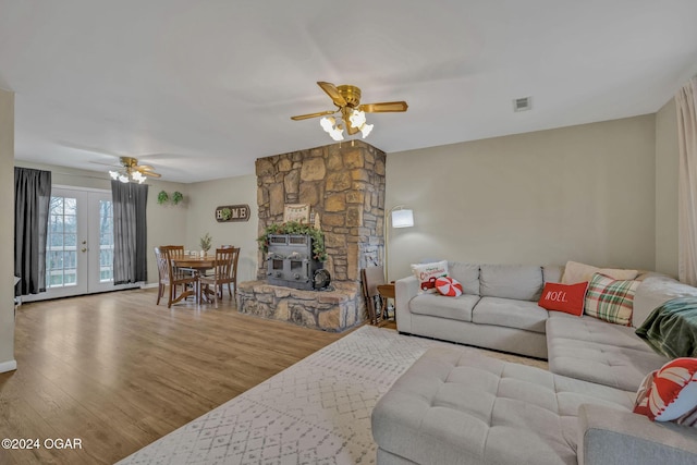 living room featuring hardwood / wood-style floors, french doors, a wood stove, and ceiling fan