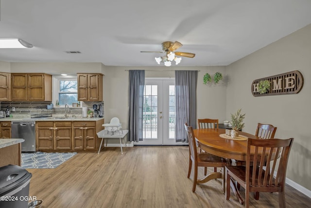 dining room with ceiling fan, french doors, sink, and light wood-type flooring