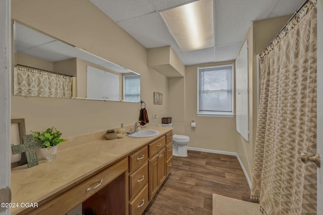 bathroom featuring vanity, hardwood / wood-style flooring, toilet, and a paneled ceiling