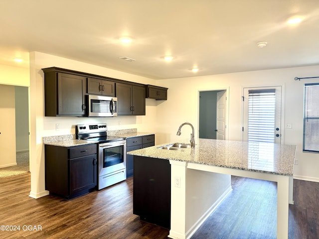 kitchen with dark hardwood / wood-style flooring, a kitchen island with sink, sink, and appliances with stainless steel finishes