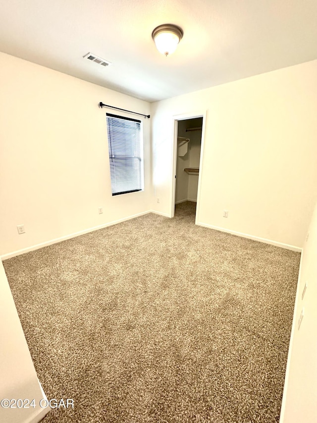 unfurnished bedroom featuring a walk in closet, carpet floors, and a closet