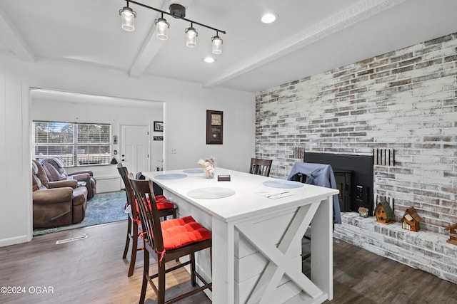 dining area featuring beamed ceiling and dark hardwood / wood-style flooring