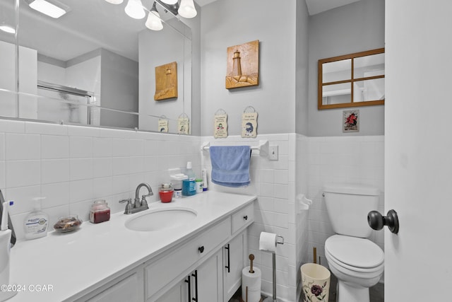 bathroom with vanity, toilet, and tile walls