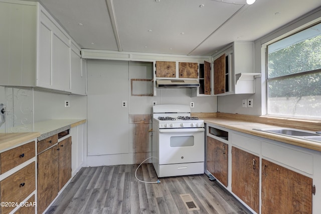 kitchen with white range with gas cooktop, white cabinetry, plenty of natural light, and light hardwood / wood-style flooring