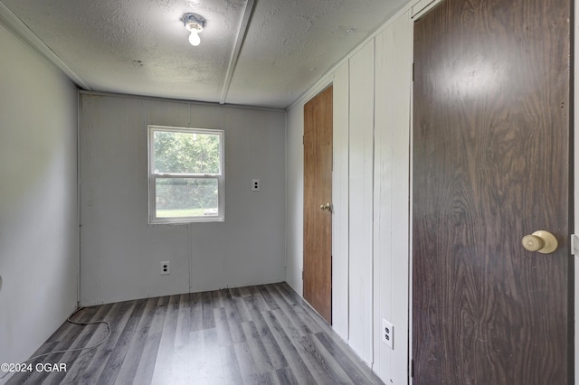 spare room featuring a textured ceiling, light hardwood / wood-style floors, and wooden walls