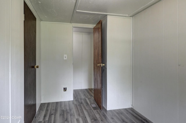 hallway with hardwood / wood-style floors, a textured ceiling, and wooden walls