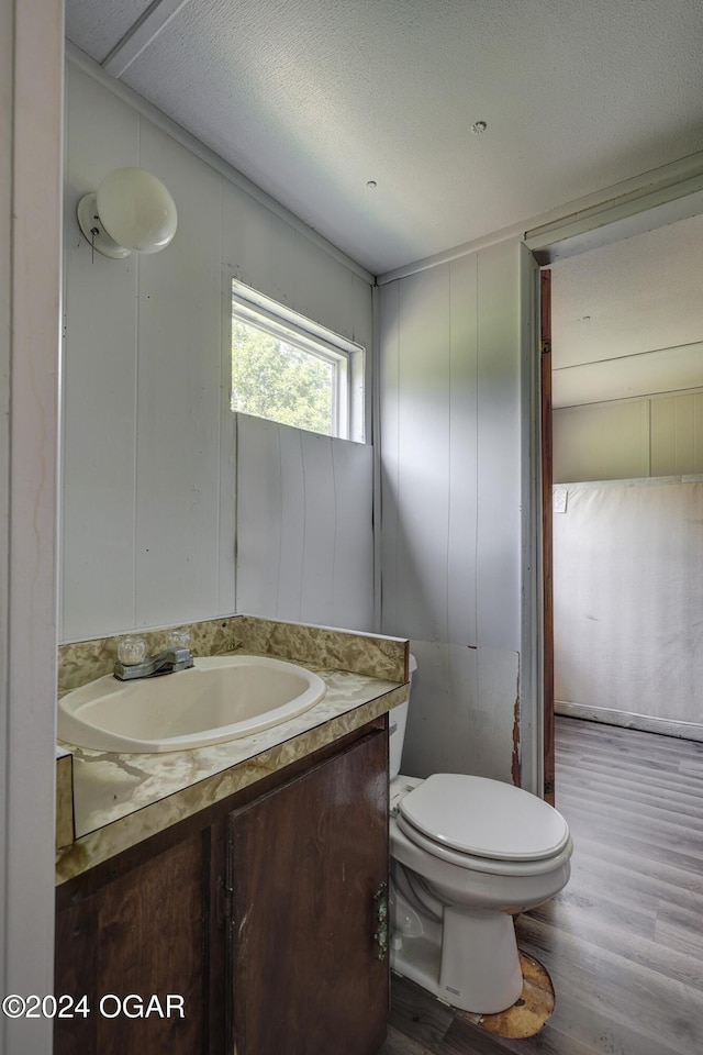 bathroom with a textured ceiling, vanity, hardwood / wood-style flooring, and toilet