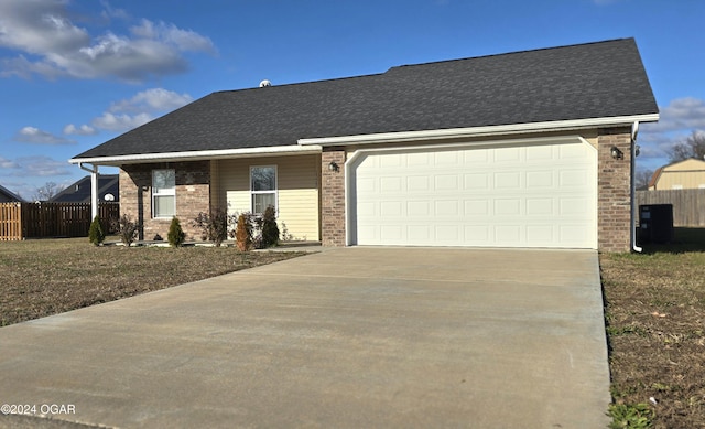 ranch-style home with a garage and central AC unit