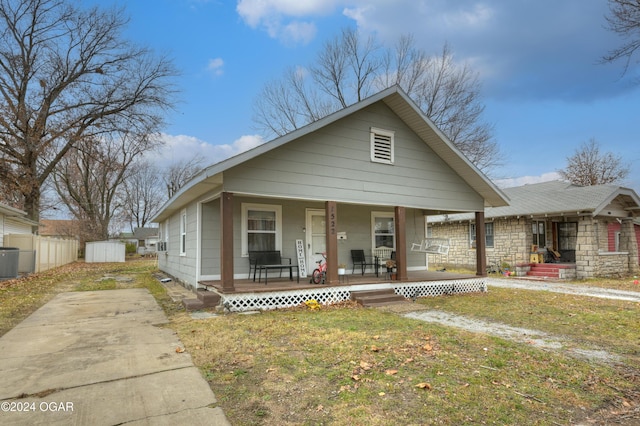 bungalow-style house featuring covered porch, a front yard, and a storage shed