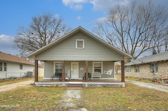 bungalow-style house featuring covered porch, central AC, and a front yard