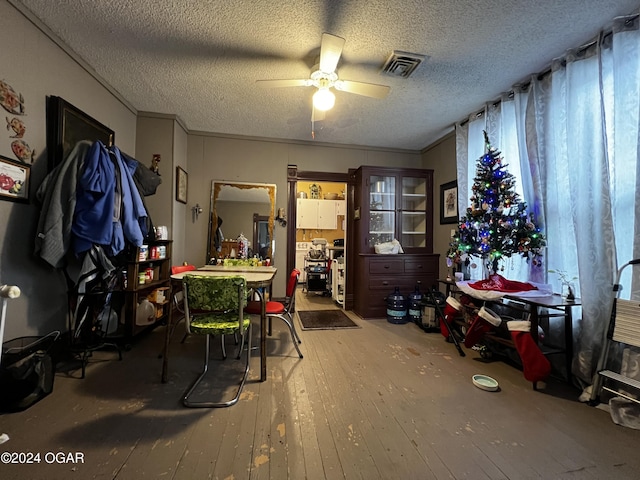 misc room with ceiling fan, crown molding, wood-type flooring, and a textured ceiling