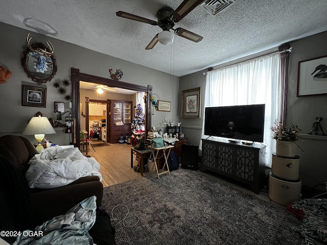 living room featuring a textured ceiling, light hardwood / wood-style floors, and ceiling fan