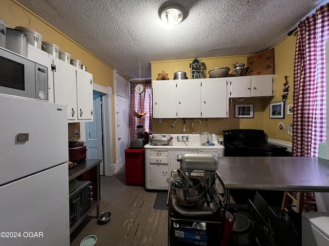 kitchen featuring a textured ceiling, white cabinets, white fridge, and black range with gas cooktop