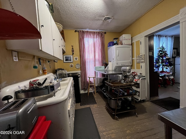 kitchen featuring dark hardwood / wood-style flooring, a textured ceiling, stacked washer and dryer, white cabinetry, and fridge