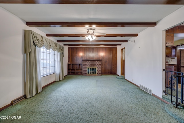 unfurnished living room featuring a fireplace, carpet floors, ceiling fan, and wooden walls