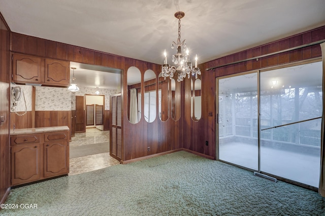 carpeted empty room with wooden walls and a chandelier