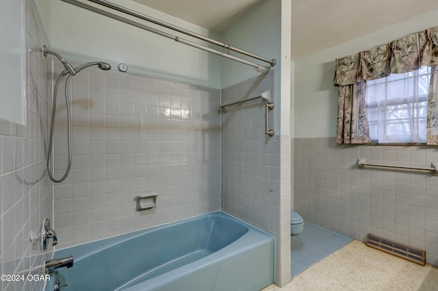 bathroom featuring tile patterned flooring, tiled shower / bath combo, tile walls, and toilet