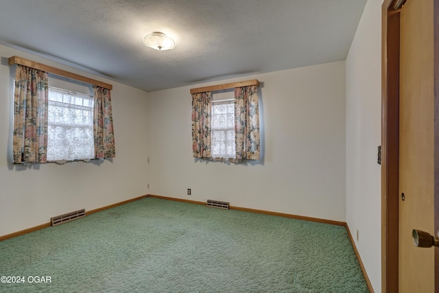 unfurnished room with plenty of natural light, carpet floors, and a textured ceiling