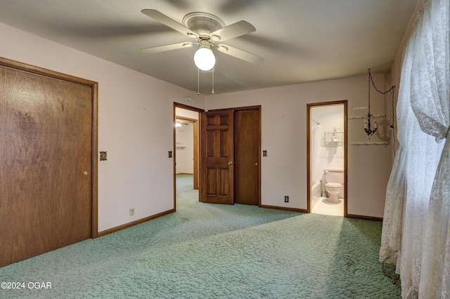 unfurnished bedroom featuring ceiling fan, light colored carpet, and ensuite bath