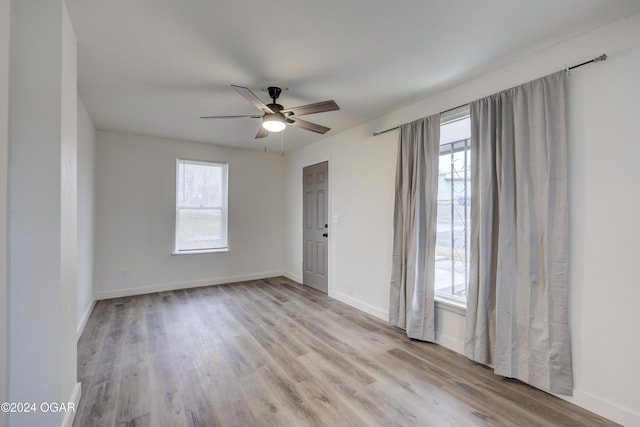 spare room featuring light wood-type flooring, plenty of natural light, and ceiling fan