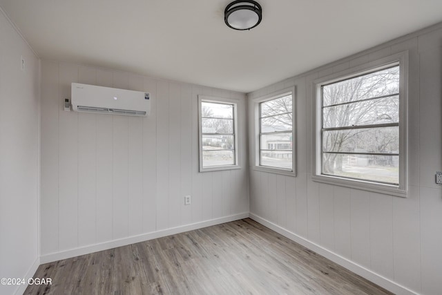 unfurnished room featuring a wall mounted AC and light hardwood / wood-style flooring