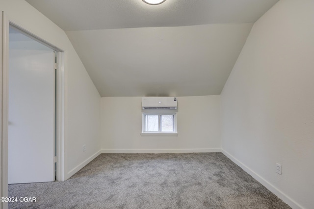 additional living space with light carpet, vaulted ceiling, and a wall unit AC