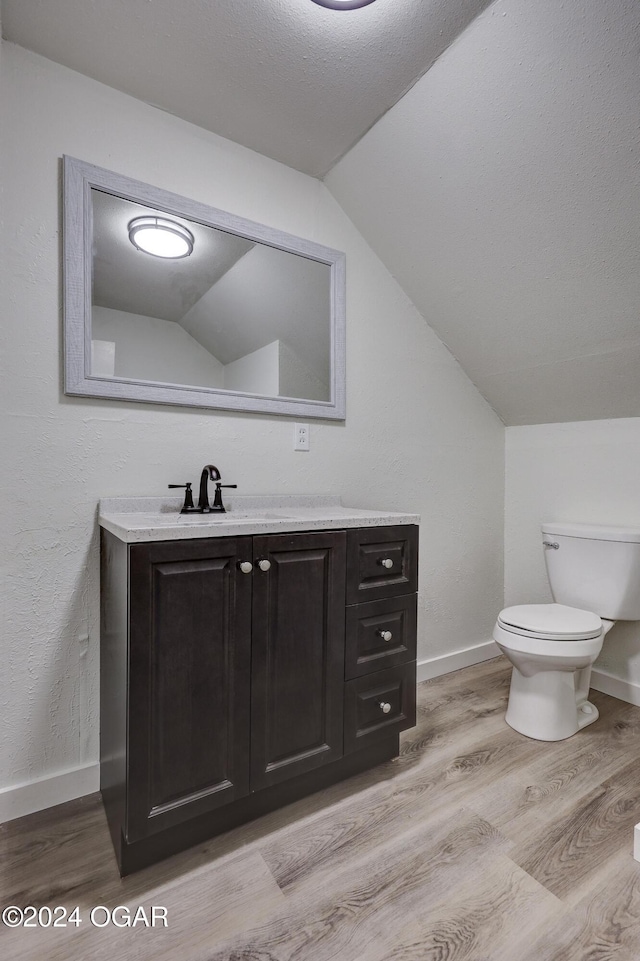 bathroom with toilet, vanity, lofted ceiling, and hardwood / wood-style flooring