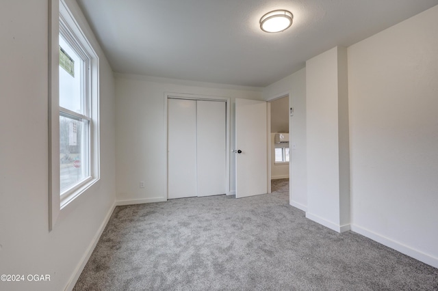 unfurnished bedroom featuring light colored carpet and a closet