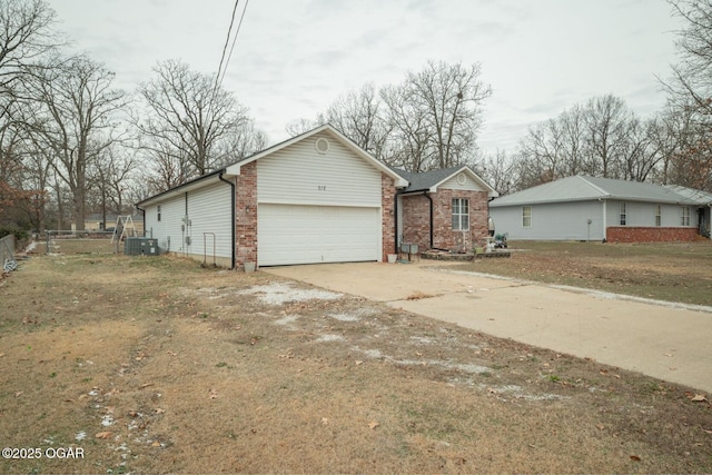 view of front of house featuring central air condition unit, a front lawn, and a garage