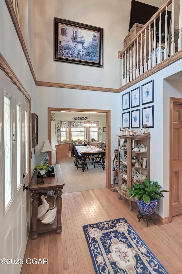 foyer entrance with a towering ceiling, wood-type flooring, and a notable chandelier