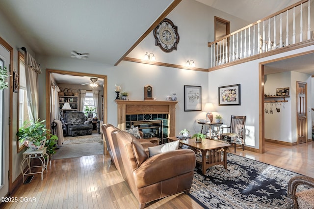 living room featuring a tiled fireplace, ceiling fan, and wood-type flooring