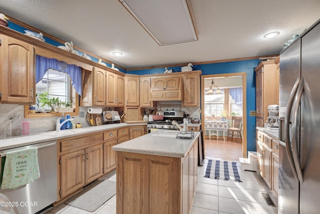 kitchen with crown molding, a kitchen island, stainless steel appliances, and light tile patterned floors