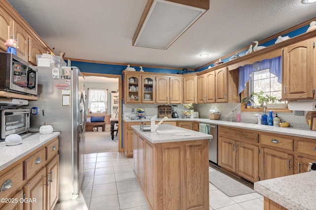 kitchen featuring a kitchen island, light tile patterned floors, stainless steel appliances, and a wealth of natural light