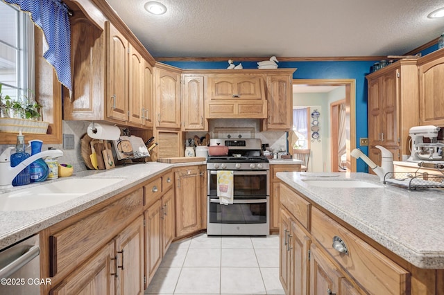 kitchen with ornamental molding, a textured ceiling, stainless steel appliances, sink, and light tile patterned floors