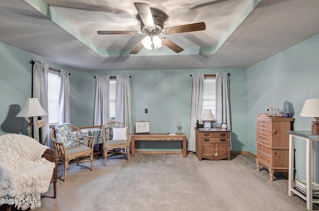 sitting room with carpet, ceiling fan, and a raised ceiling