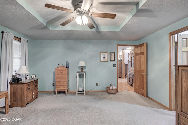 carpeted bedroom with a raised ceiling, ceiling fan, and a textured ceiling