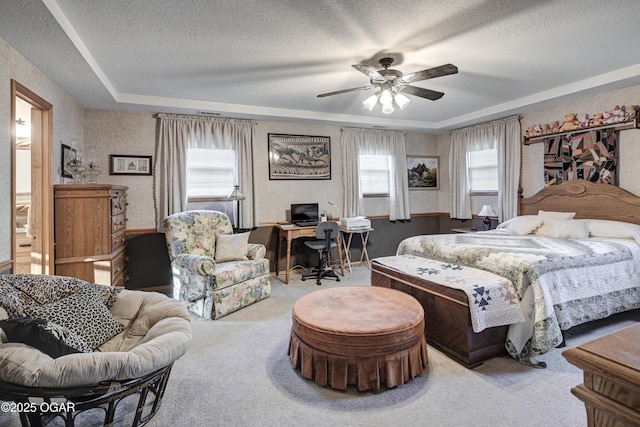 bedroom featuring carpet flooring, a textured ceiling, a tray ceiling, and ceiling fan