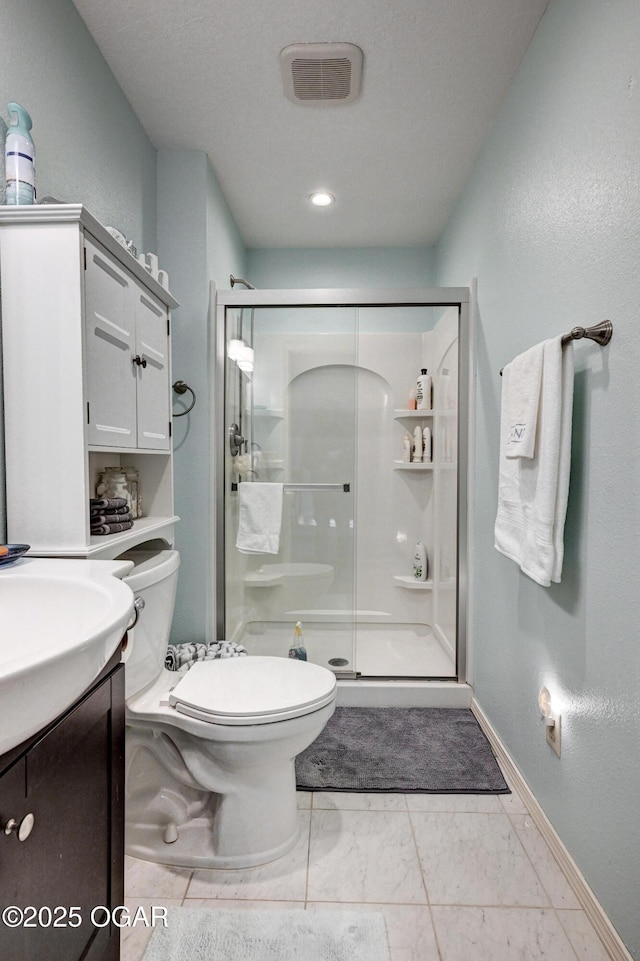 bathroom featuring vanity, toilet, a shower with door, and a textured ceiling