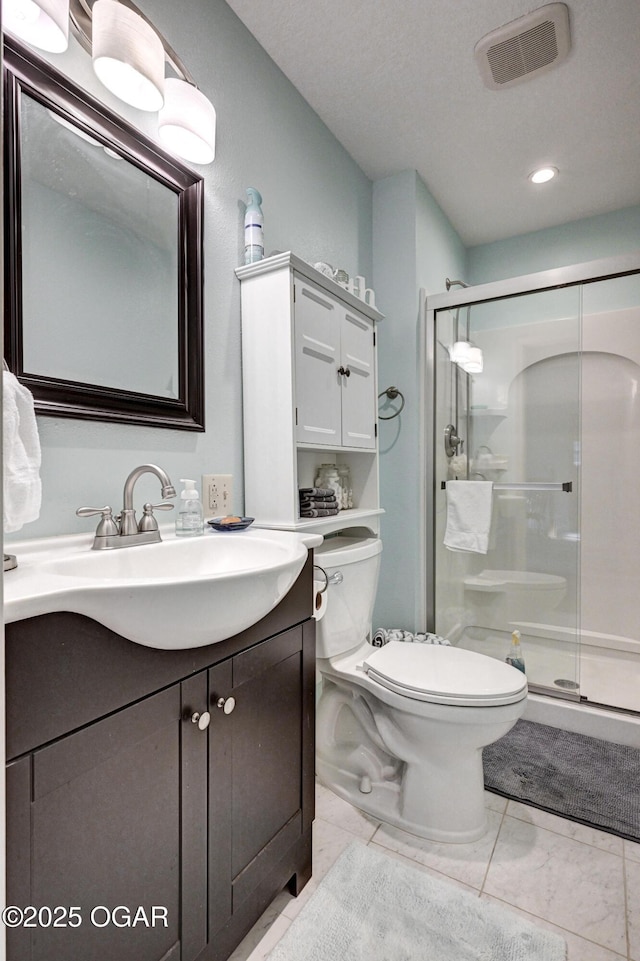 bathroom with vanity, toilet, a shower with shower door, and a textured ceiling