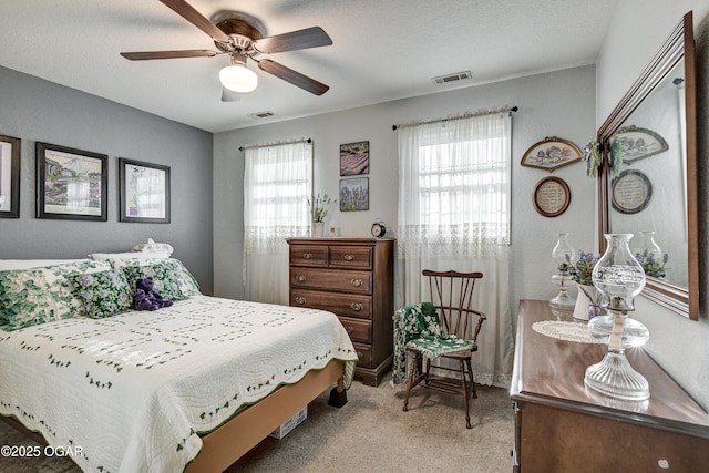 bedroom featuring a textured ceiling, light colored carpet, and ceiling fan