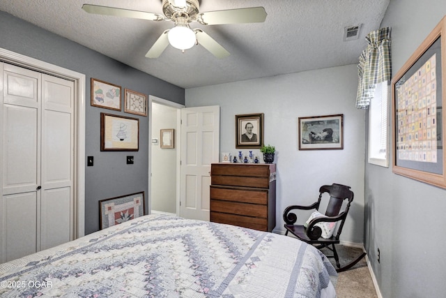 carpeted bedroom featuring ceiling fan, a closet, and a textured ceiling