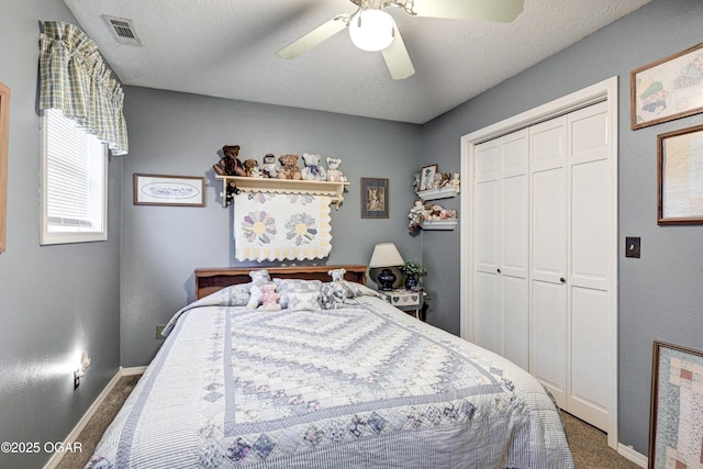 carpeted bedroom with ceiling fan, a textured ceiling, and a closet