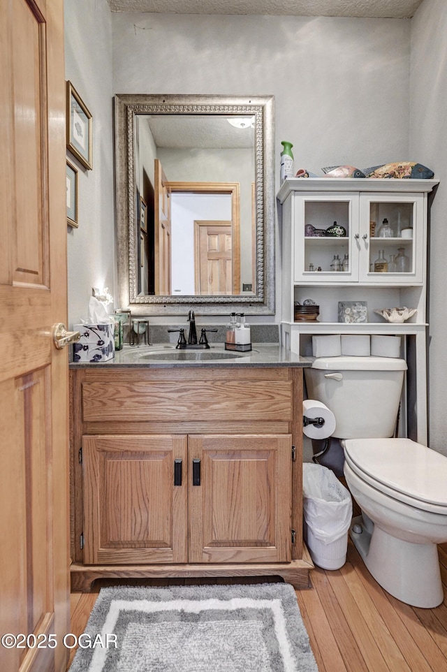 bathroom with hardwood / wood-style flooring, vanity, and toilet