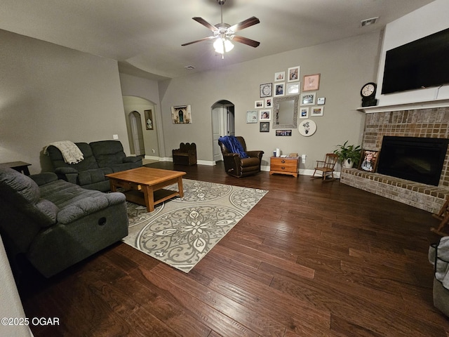 living room featuring hardwood / wood-style floors, ceiling fan, and a brick fireplace