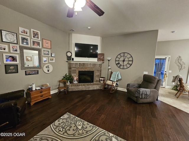 living room featuring hardwood / wood-style flooring, ceiling fan, and a brick fireplace