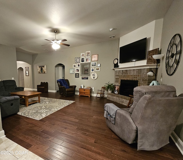 living room with ceiling fan, dark hardwood / wood-style flooring, and a fireplace