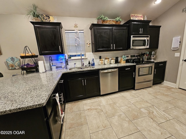 kitchen with light stone countertops, appliances with stainless steel finishes, backsplash, vaulted ceiling, and sink